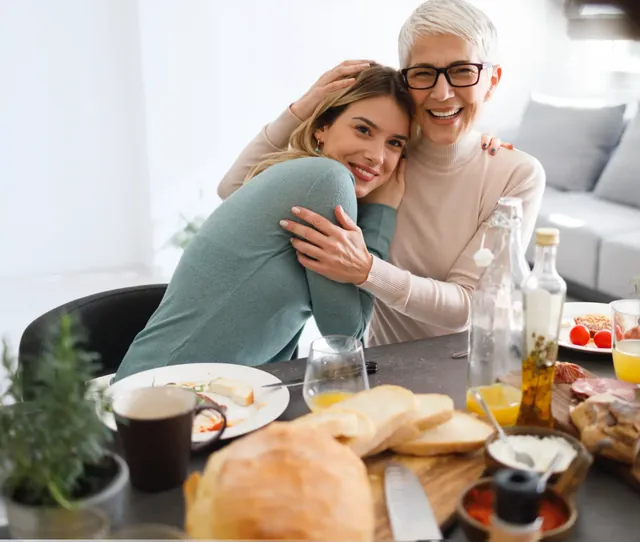 Grandmother and granddaughter hugging and laughing at a family meal